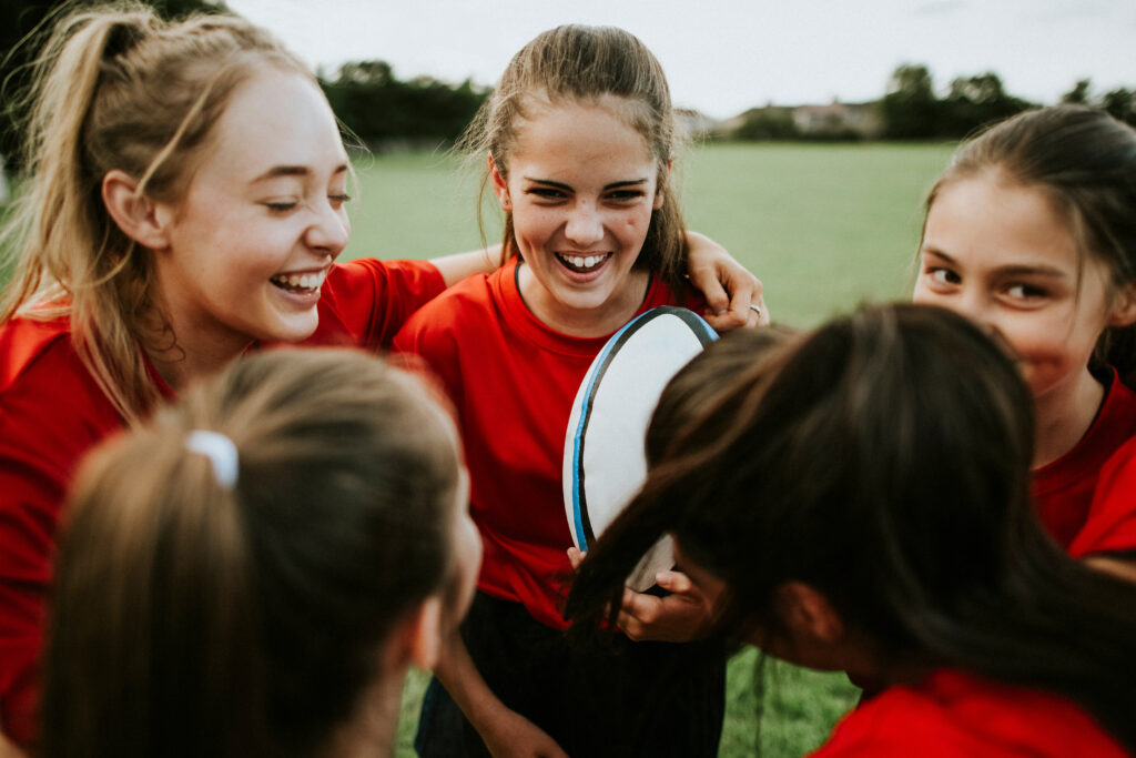 Girls showing good sportsmanship and teamwork during a rugby PE lesson